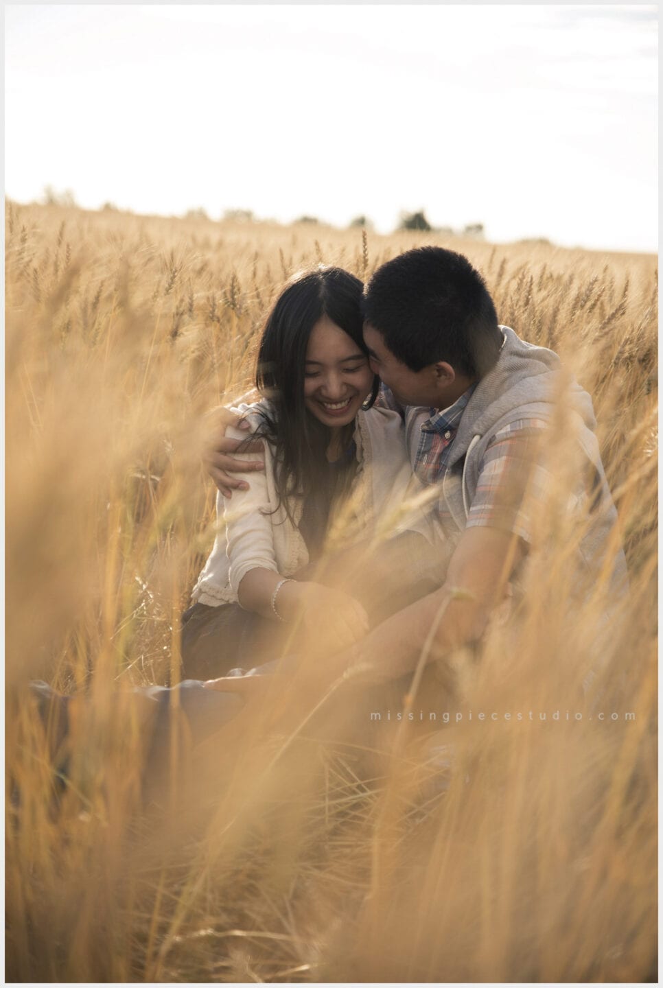 a couple whispering into each other at a picnic in a wheat field