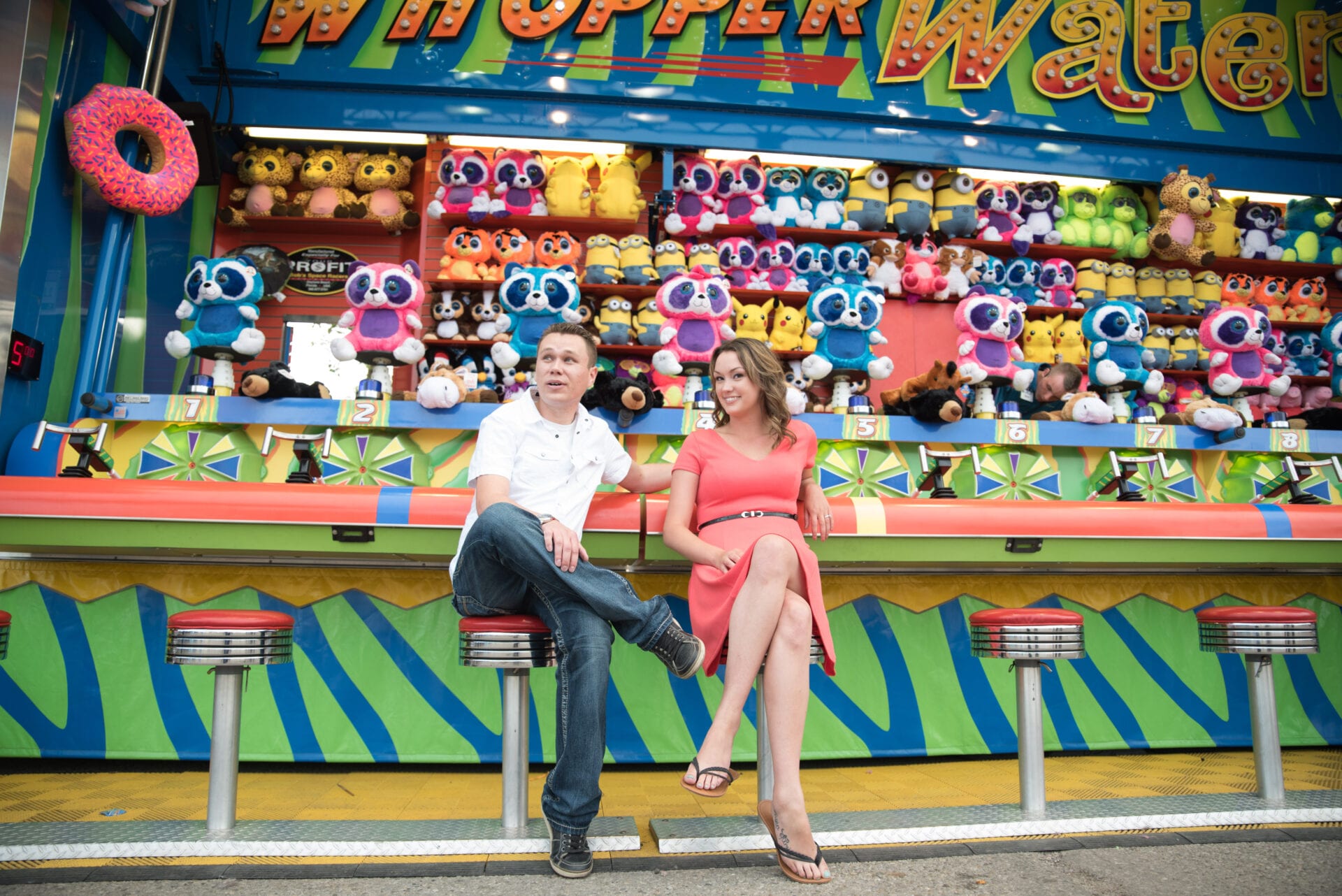 A couple sitting at a carnival game posing for a photo