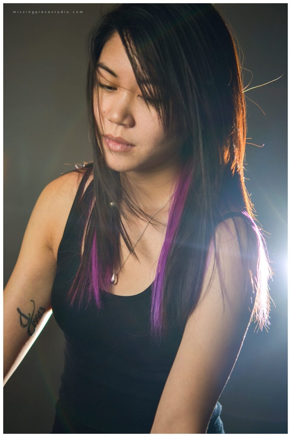 Female model with purple streaks and a tattoo on right arm