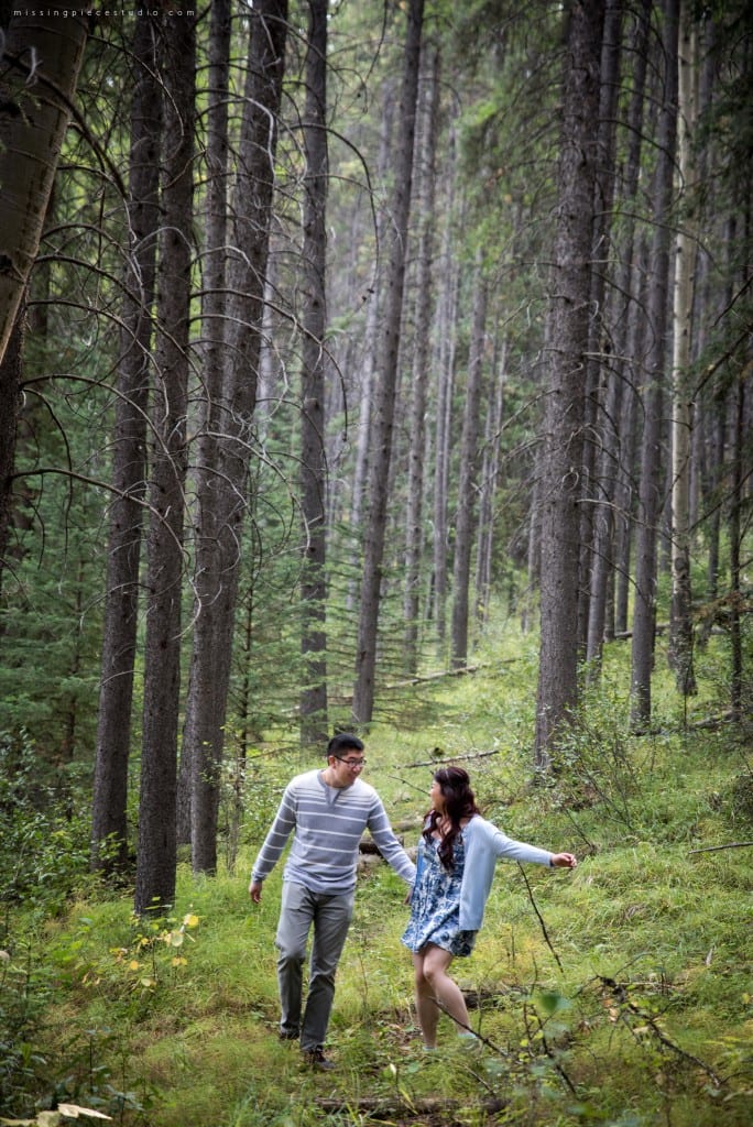 A couple running down the Banff forest in the summer near Calgary, Canada.