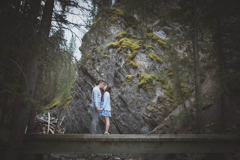 A couple kissing on a bridge at a Banff forest in the summer near Calgary, Canada.